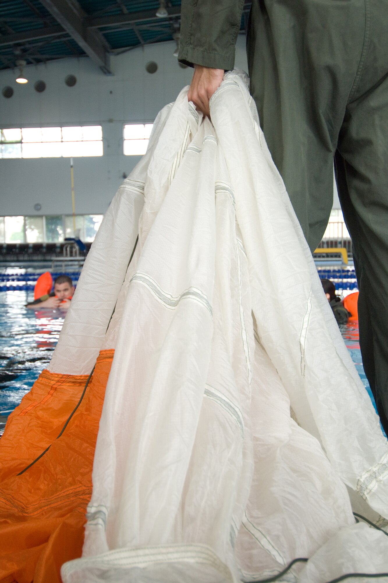 YOKOTA AIR BASE, Japan --Staff Sgt. Benjamin Rosciglione, 374th Operations Support Squadron Survival, Evasion Resistance and Escape specialist, prepares a parachute canopy during water survival refresher training recently at the Natatorium Indoor Pool. SERE technicians teach the course to aircrew members at least once every three years. The training is especially important for Yokota aircrews, who routinely fly long distances over large bodies of water in the Pacific Rim. (U.S. Air Force photo/Osakabe Yasuo) 



