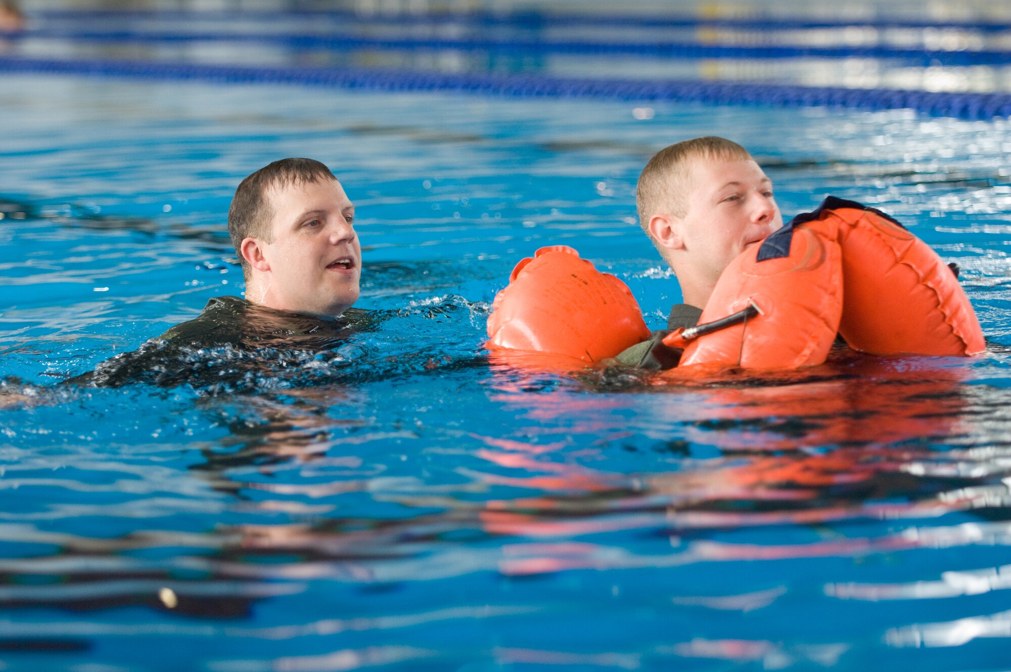 YOKOTA AIR BASE, Japan -- Staff Sgt. Benjamin Rosciglione, 374th Operations Support Squadron Survival, Evasion, Resistance and Escape specialist, (left) instructs an aircrew member on how to drag another crew member to safety during water survival refresher training recently at the Natatorium Indoor Pool. SERE technicians teach the course to aircrew members at least once every three years. The training is especially important for Yokota aircrews, who routinely fly long distances over large bodies of water in the Pacific Rim. (U.S. Air Force photo/Osakabe Yasuo) 

