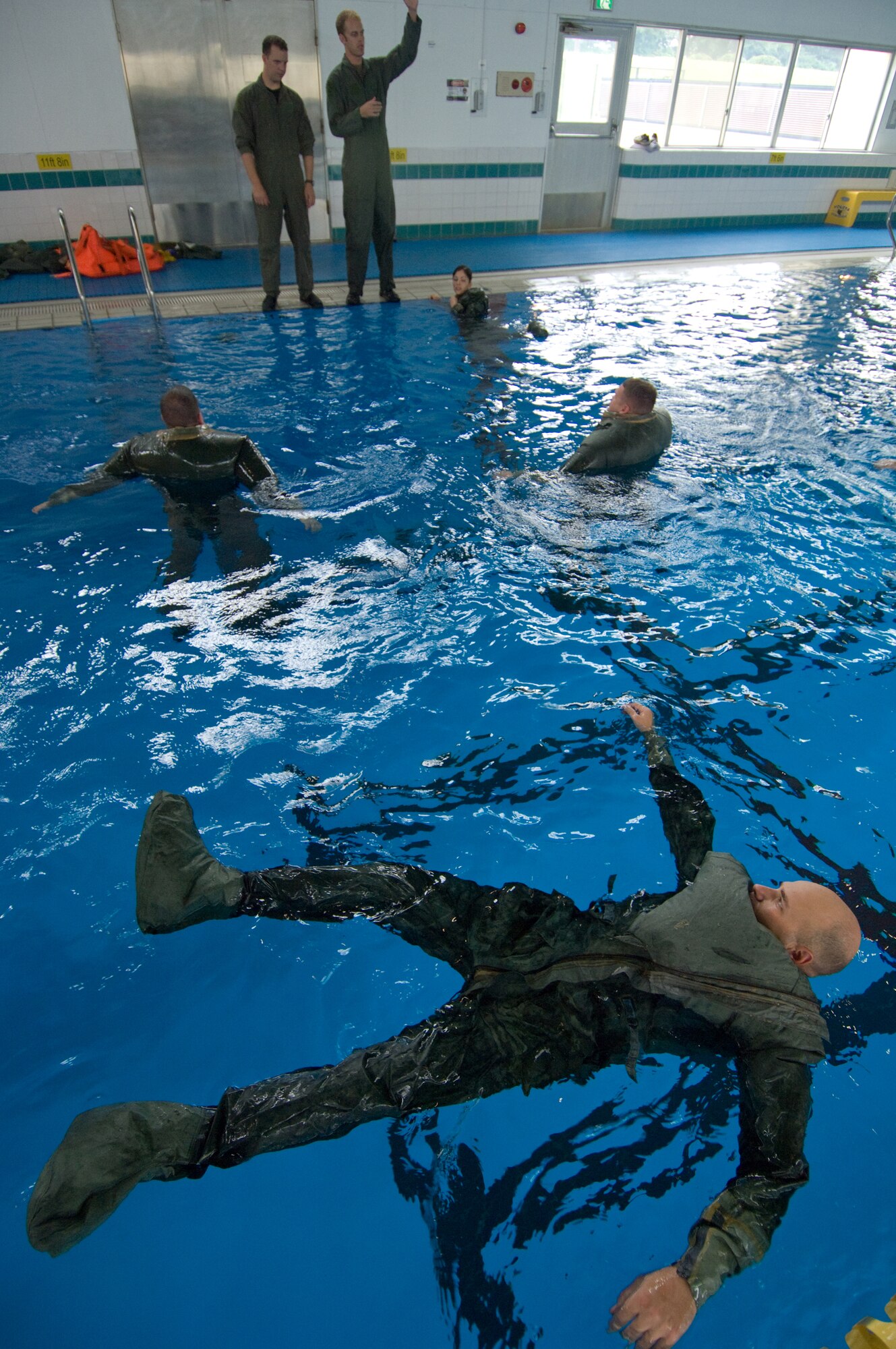 YOKOTA AIR BASE, Japan -- Maj. Daniel Cordes, 374th Airlift Wing Inspector General Office (foreground), listens to instructions during water survival refresher training recently at the Natatorium Indoor Pool. Survival, evasion, resistance and escape technicians teach the course to aircrew members at least once every three years. The training is especially important for Yokota aircrews, who routinely fly long distances over large bodies of water in the Pacific Rim. (U.S. Air Force photo/Osakabe Yasuo) 