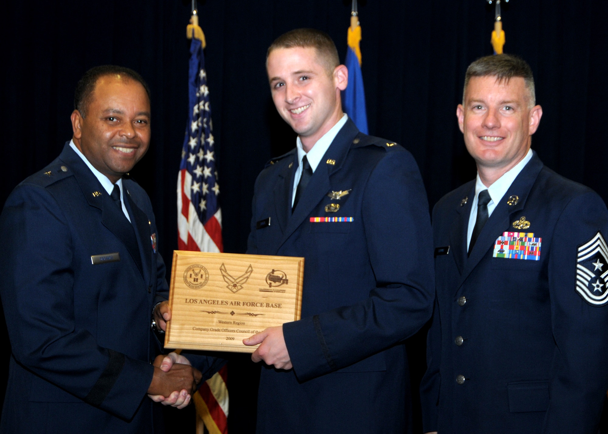 Lt. Brian Dougal (center), Los Angeles AFB Company Grade Officers Council treasurer, accepts the award on behalf of the organization. The base CGOC recently won the Western Regions Best CGOC of the Year and was honored at the monthly Promotion and Recognition Ceremony at the Gordon Conference Center, Aug. 31. Brig. Gen Samuel Greaves (left), Space and Missiles Systems Center vice commander, and Chief Master Sgt. Stephen Ludwig (right), SMC Command Chief Master Sgt., preside. (Photo by Joe Juarez)

