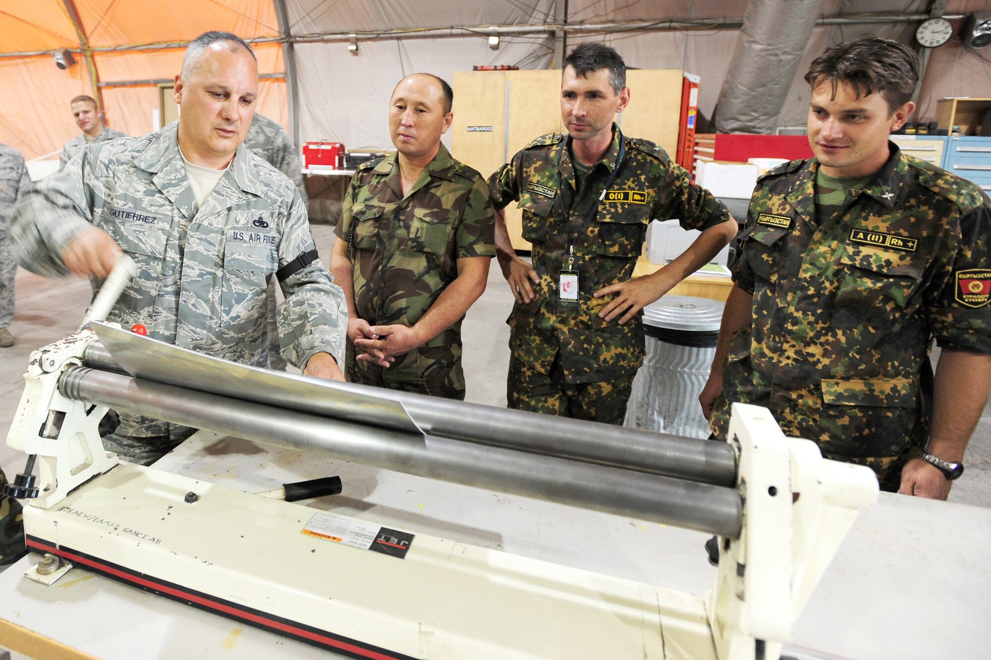 Master Sgt. Xavier Gutierrez demonstrates machinery to Kyrgyz ministry of defense officials Lt. Col. Vakhiddulla Toktakhunov, Maj. Andrey Mescheryakov, and Capt. Denis Satir, Aug. 25, 2009 during a visit to the Transit Center at Manas, Kyrgyzstan. The Kyrgyz ministry of defense got a firsthand look at maintenance facilities and a KC-135 Stratotanker while touring the Transit Center. Sergeant Gutierrez is the 376th Expeditionary Aircraft Maintenance Group sheet metal NCO in charge. (U.S. Air Force photo/Senior Airman Steele C. G. Britton) 