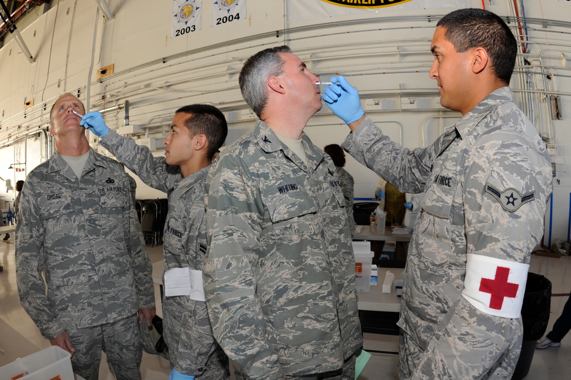 PETERSON AIR FORCE BASE, Colo. -- Airman 1st Class Kristopher Hawkins and Airman Jonathan Rivera, 21st Medical Operations Squadron medical technicians, administer the live FluMist vaccine to Chief Master Sgt. Tim Omdal, 21st Space Wing command chief, and Col. Stephen Whiting, 21st SW commander, during the 21st SW commander’s call Sept. 3 in Hangar 140. Flu season starts in October and continues into May. The flu vaccine is mandatory for all active duty personnel and optional for military ID card holders, and is designed to increase readiness to support deployable Airmen as well provide installation support and protection. The vaccine was for the seasonal flu; servicemembers can expect a two-part H1N1 vaccine in October or November. (Air Force photo by Rob Bussard)
