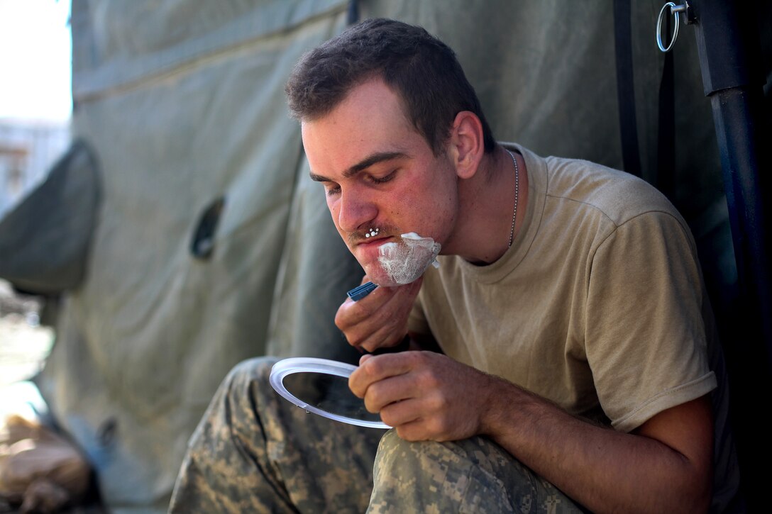 U.S. Army Spc. Kevin Anderson shaves outside his tent at Combat Outpost Tangi in the Wardak province, Afghanistan, Sept. 2, 2009. Anderson is a mortar operator assigned to the 10th Mountain Division‘s Company A, 2nd Battalion, 87th Infantry Regiment, 3rd Brigade Combat Team.