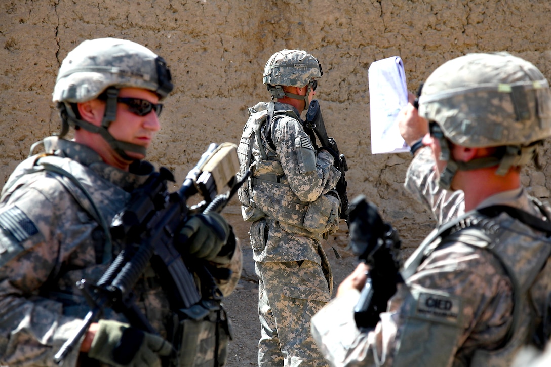 A U.S. Army soldier provides security while 1st Lt. Phillip Cooper, right, 
his platoon leader, speaks with Maj. Mike Slevin, left, during a route clearance mission in the Tangi Valley, Wardak province, Afghanistan, Sept. 2, 2009.