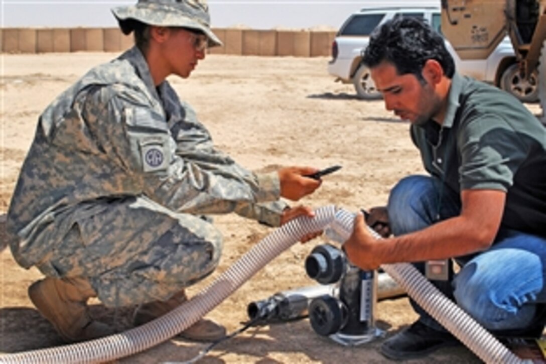U.S. Army Spc. Rachael Potts and an Iraqi engineer prepare a hose that will run dirty water through a solar-powered water filtration system during a demonstration for several Madain region engineers on Forward Operating Base Hammer, Iraq, Sept. 5, 2009.