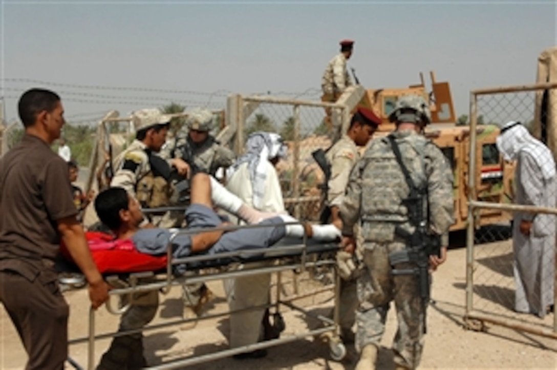 U.S. and Iraqi soldiers and Iraqi civilians help escort a patient from a medical facility during a combined medical mission in Baghdad, Sept. 1, 2009. The U.S. soldiers are assigned to the 1st Cavalry Division's Heavy Brigade Combat Team.