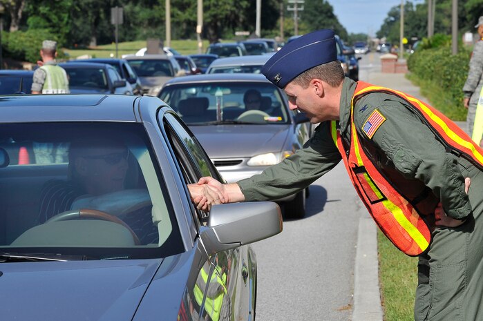 Col. John Wood shakes hands with Brian Daly at the Dorchester Road gate during the safety send off prior to the Labor Day weekend here Sept. 3. The safety send off was held as a reminder of the importance of safety during the holiday weekend. Colonel Wood is the 437th Airlift Wing commander. (U.S. Air Force photo/James Bowman)