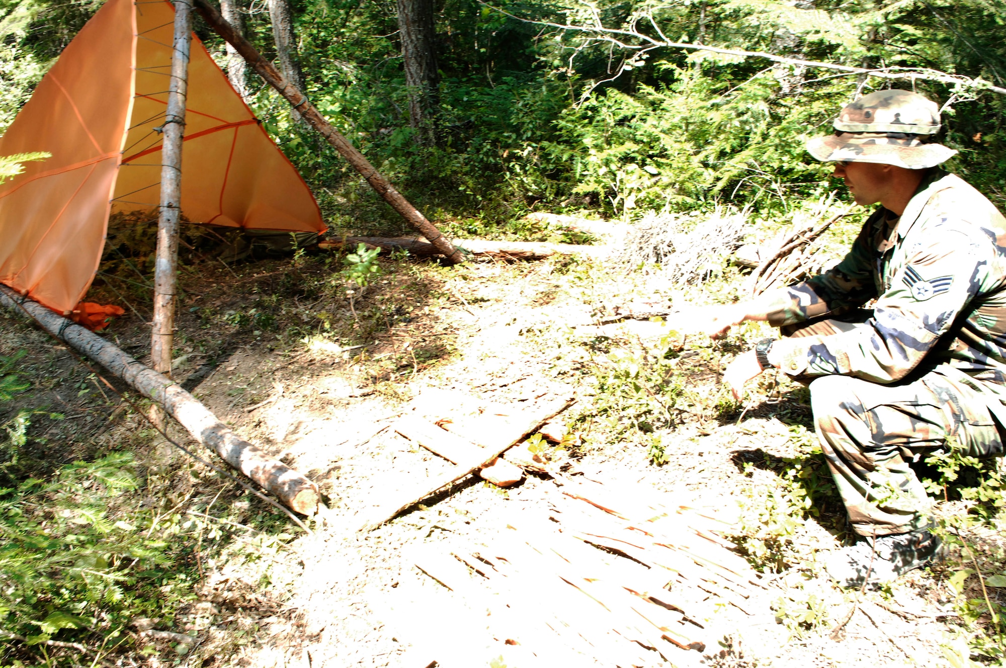 A 66th Training Squadron instructor assesses a shelter constructed by a student during the Familiarization phase of training. Survival, Evasion, Resistance and Escape training is a six-month course that turns regular Airmen into SERE specialists and, eventually, instructors. (U.S. Air Force photo/Senior Airman Emerald Ralston)