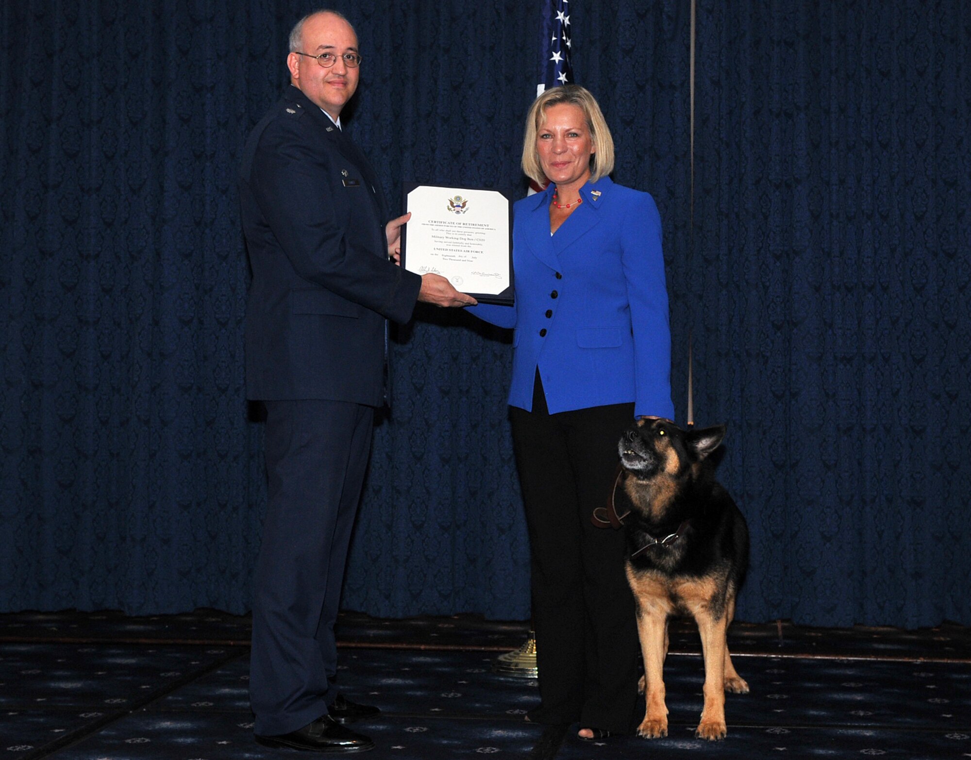 Lt. Col. Allan Conkey, 11th Security Forces Squadron commander, presents J.T. Gabriel, military working dog Ben’s new owner, Ben’s retirement certificate during his retirement ceremony Sept. 8 at the Bolling Club. Ben served 11 years as a dual-certified patrol and narcotics-detector military working dog in the Air Force. (U.S. Air Force photo by Senior Airman Marleah Miller)