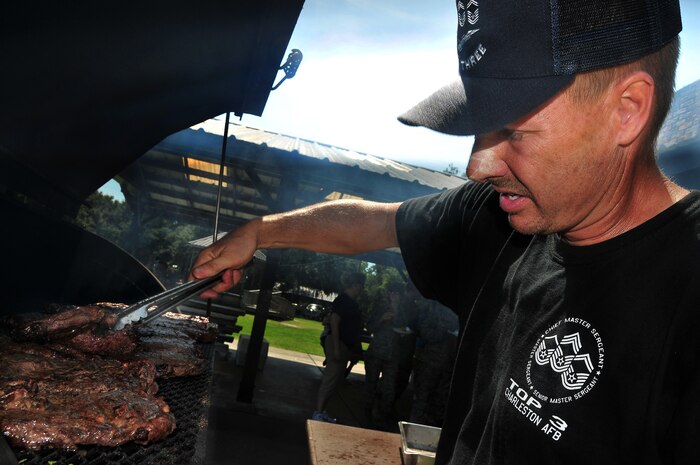 Senior Master Sgt. Brian Davis bends a cut of meat to check its color at the Top 3 Steak-Out held at hte picnic grounds here Sept. 3. Approximately 400 steaks were cooked to order and sold with potatoes, corn and drinks to help raise money for the Top 3 Oktoberfest, a free junior enlisted appreciation event, scheduled for Oct. 16. Sergeant Davis is the chief enlisted manager with the 437th Civil Engineer Squadron. (U.S. Air Force photo/Staff Sgt. Daniel Bowles)