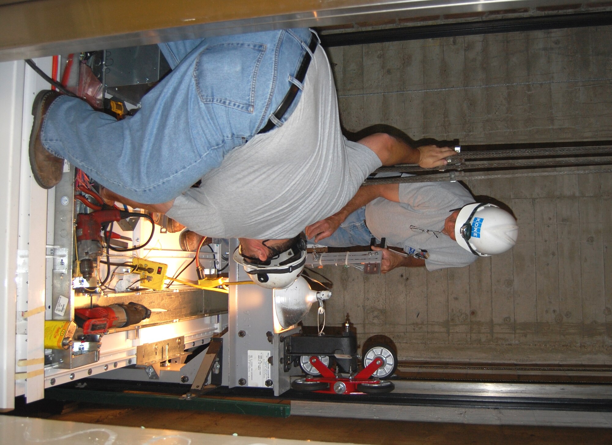 Kone Elevator technicians Jeff Combe, foreground, and Mike Ison prepare to place a normal terminal stopping device atop the elevator cab they have been building at Keesler Medical Center. Elevator 1 is the first of the three-bank elevators in the rear of the main medical center building, being completely replaced. It should be operational this month. Work on all three elevators should be completed early next year. The original elevators were installed when the medical center was constructed in 1957. First Lt. Zane Holland, the medical center’s director of plant operations, said the new elevators will be about 3-4 inches wider and deeper, enabling them to
accommodate a variety of patient beds and increasing the number of elevators
available to transport patients. They also will have the newest technology, will be more reliable and meet current safety codes. The two “A-Tower” elevators in the front of the main building were refurbished earlier with new wall coverings and ceilings.  (U.S. Air Force photo by Steve Pivnick)