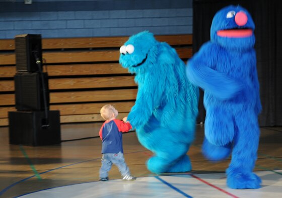 RAF MILDENHALL, England -- Ryan Steffen, 2, stormed the stage at the conclusion of the Sesame Workshop/United Service Organization's free traveling tour in the Northside Fitness Center Sept. 8. Luckily, Cookie Monster was able to guide Ryan back to the seating area where he watched the remainder of "Talk, Listen, Connect," a performance designed to teach young children about deployments and parents returning home changed due to combat-related injuries. (U.S. Air Force photo/Senior Airman Thomas Trower)