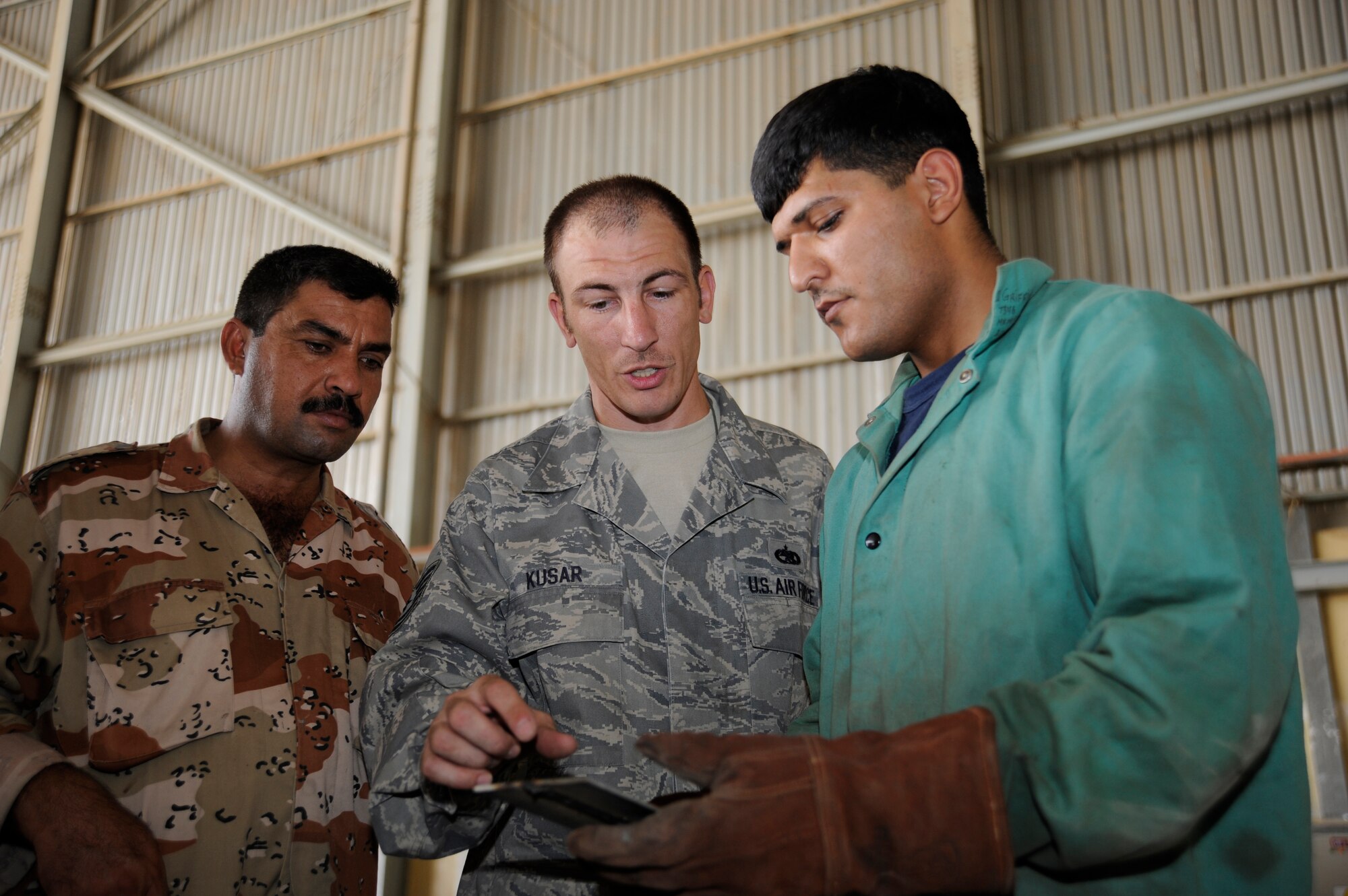 NEW AL MUTHANNA AIR BASE, Iraq -- Tech. Sgt. William Kusar, aircraft structural maintenance and metals technician advisor assigned to the 321st Air Expeditionary Advisor Squadron, evaluates an Iraqi maintenance airman's weld and provides feedback during a training session here Sept. 5, 2009. Sergeant Kusar's training ensures the Iraqi airmen will be fully capable of performing structural repairs on their C-130 aircraft. Sergeant Kusar is deployed from Charleston Air Force Base, S.C. (U.S. Air Force photo/Tech. Sgt. Johnny L. Saldivar)