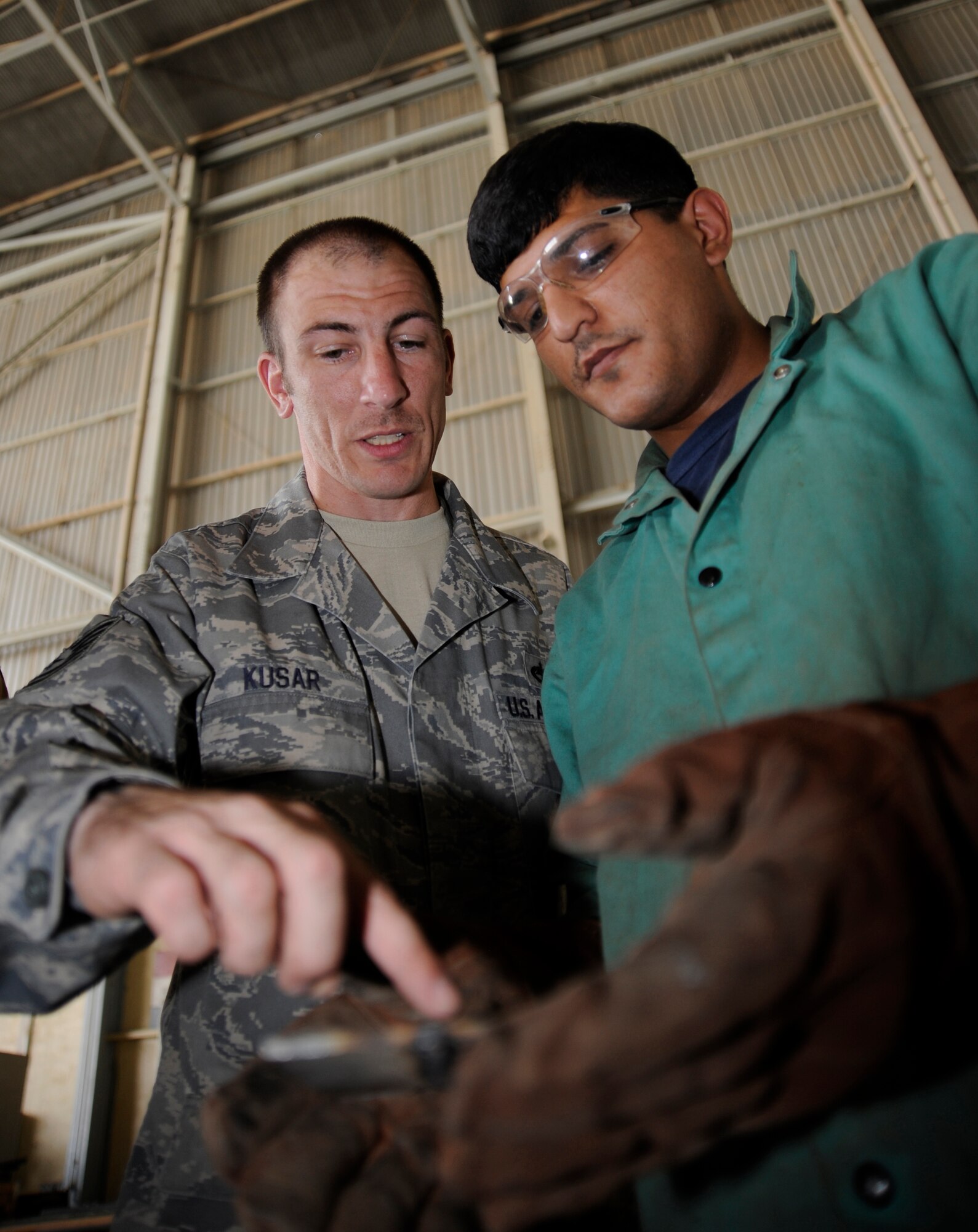 NEW AL MUTHANNA AIR BASE, Iraq -- Tech. Sgt. William Kusar, aircraft structural maintenance and metals technician advisor assigned to the 321st Air Expeditionary Advisor Squadron, evaluates an Iraqi maintenance airman's weld and provides feedback during a training session here Sept. 5, 2009. Sergeant Kusar?s training ensures the Iraqi airmen will be fully capable of performing structural repairs on their C-130 aircraft. Sergeant Kusar is deployed from Charleston Air Force Base, S.C. (U.S. Air Force photo/Tech. Sgt. Johnny L. Saldivar)