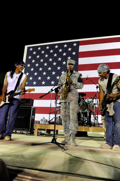 Kadena Airman 1st Class Theodore Wilkins, deployed from the 18th Security Forces Squadron and assigned to the 732nd Expeditionary SFS, plays the saxophone on stage with the Los Lonely Boys for a mixed crowd of Soldiers, Airmen, Sailors, and civilians at Contingency Operating Base Speicher, Iraq, Sept. 4, 2009. The Grammy Award winning Rock-N-Roll trio performed at COB Speicher as part of a military appreciation concert tour in the AOR. 
(U.S. Air Force photo by Staff Sgt. Luke P. Thelen/Released)