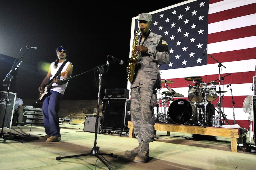 Kadena Airman 1st Class Theodore Wilkins, deployed from the 18th Security Forces Squadron and assigned to the 732nd Expeditionary SFS, plays the saxophone on stage with the Los Lonely Boys for a mixed crowd of Soldiers, Airmen, Sailors, and civilians at Contingency Operating Base Speicher, Iraq, Sept. 4, 2009. The Grammy Award winning Rock-N-Roll trio performed at COB Speicher as part of a military appreciation concert tour in the AOR. 
(U.S. Air Force photo by Staff Sgt. Luke P. Thelen/Released)