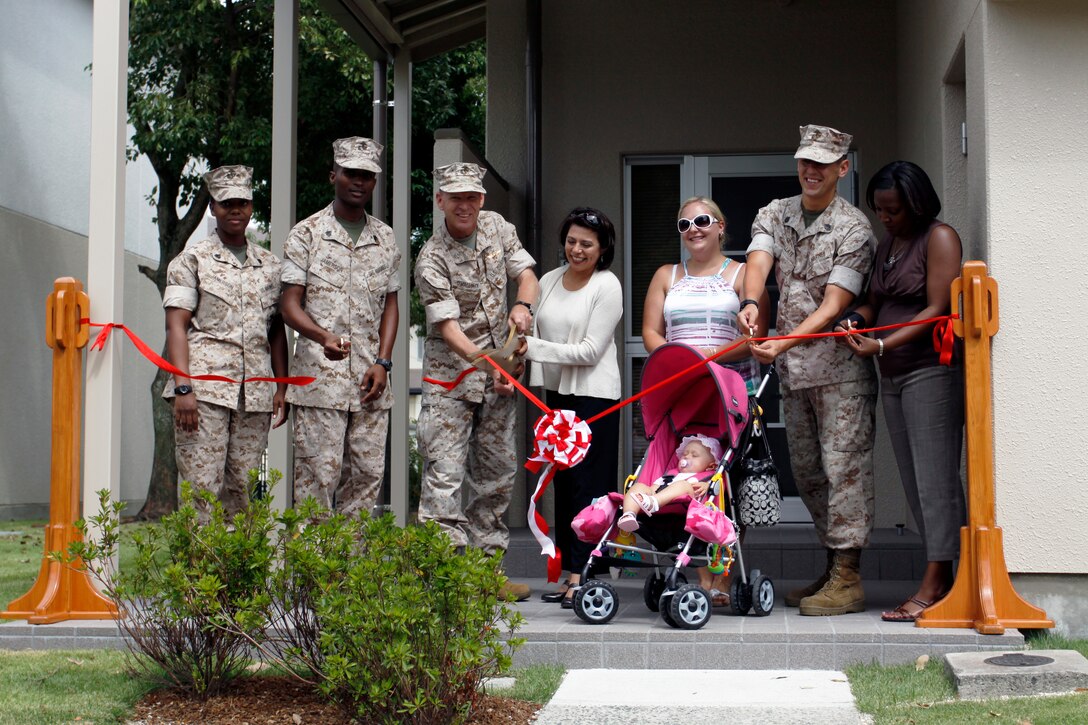 Col. Michael A. O’Halloran, station commanding officer, and his wife, Candice O’Halloran, along with station members slated to move into the newly renovated townhomes here cut a ribbon in front of one of the renovated homes in the Monzen area here during a ribboncutting ceremony officially declaring the residences ready to be lived in Sept. 9. Thirty-two townhouse units were made available for use after undergoing months of renovations. The newly renovated homes have been outfitted with new carpet, ceilings, countertops, tiles, kitchenettes, bathrooms, cabinets and dishwashers. Approximately 66 more station homes have been scheduled to undergo the same renovations.