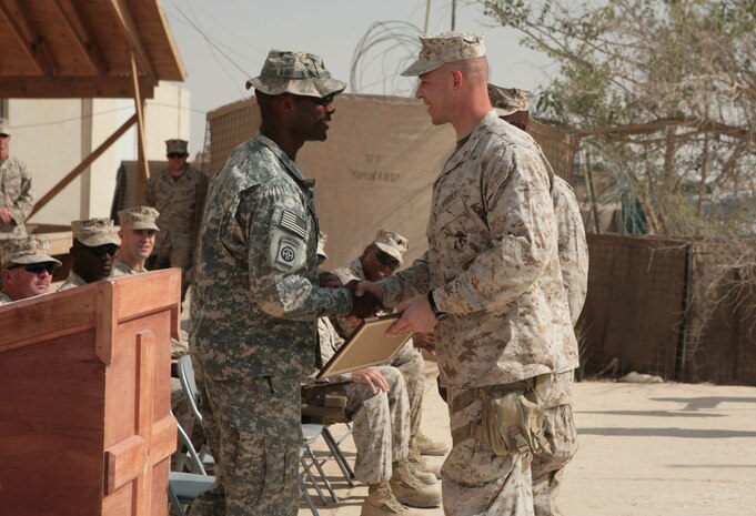 Maj. Christian Rankin, commanding officer (right), 1st Battalion, 8th Marine Regiment, shakes hands with Lt. Col. Xavier T. Brunson, commanding officer of 1st Bn., 504th Parachute Infantry Regiment, 82nd Airborne Division, (second from left) during the transfer of authority ceremony at Camp Al Taqaddum, Iraq, Sept. 10, 2009.  The Marines of 1st Bn., 8th Marines are leaving Iraq after accomplishing their mission in support of Operation Iraqi Freedom since March 2009. (Photograph courtesy of Gunnery Sgt. Katesha Washington)
