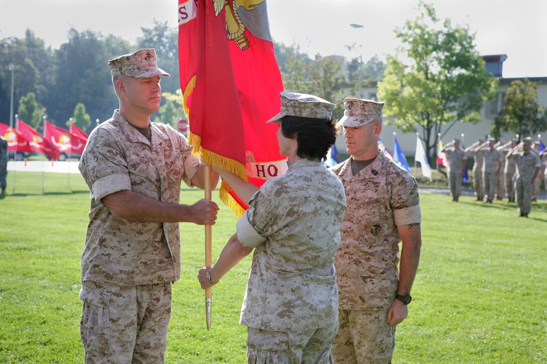 Brig. Gen. Paul W. Brier {LEFT}, incoming commander, Marine Forces Europe and Africa, receives the organizational colors from Maj. Gen. (Sel) Tracy L. Garrett, outgoing commander, while Sgt. Maj. Joseph J. Leshinsky observes, during a change of command ceremony here at the 6th Army Support Group Parade Field. The two units, MARFOREUR and MARFORAF, are responsible for coordinating Marine Corps-related exercises, operations and humanitarian assistance projects in support of the U.S. European Command, and U.S. Africa Command. Activities include various mobile training teams, humanitarian aid and military-to-military training events throughout Europe and Africa. (U.S. Marine Corps photo by Cpl. Lydia M. Davey)