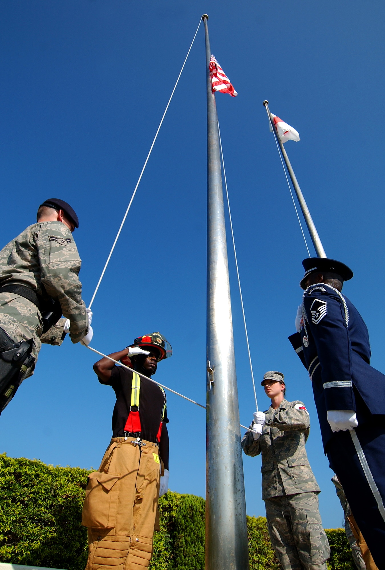 Kadena Airmen post the American flag, the Japanese flag, and the NATO flag during Taps at the 9/11 memorial ceremony near the wing building here. The ceremony acknowledged those who risked their lives to save the victims of the tragic events of September 11, 2001. The ceremony also paid tribute to the men and women of the U.S. Armed Forces who have served in the military whether deployed or at home station since these events.  (U.S. Air Force photo/Tech. Sgt. Reynaldo Ramon) 

