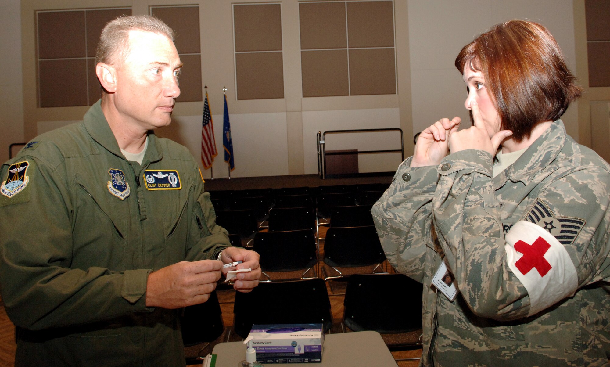 BUCKLEY AIR FORCE BASE, Colo. -- Tech. Sgt. Amber Kay, 460th Medical Operations Squadron (right) explains to Col. Clint Crosier, 460th Space Wing commander, how to use the flu mist Sept. 10. All active-duty military must get their flu immunizations today by 3 p.m. or Monday at the Leadership Development Center. (U.S. Air Force photo by Tech. Sgt. Shirley Henderson)