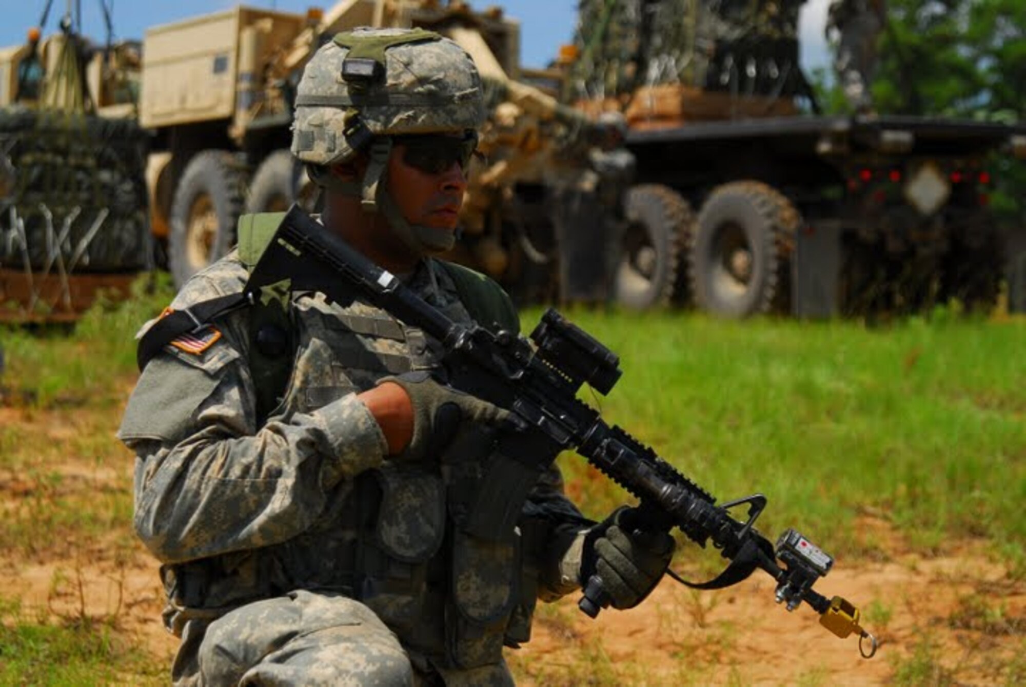 An army soldier maintains a perimeter for opposing forces as other members of the 10th Mountain Division load supply pallets onto a transport Aug 21. Soldiers from the 10th Mountain Division exercised their ability to secure and retrieve supplies from a drop zone. (U.S. Air Force photo by Staff Sgt. Juan Torres)
