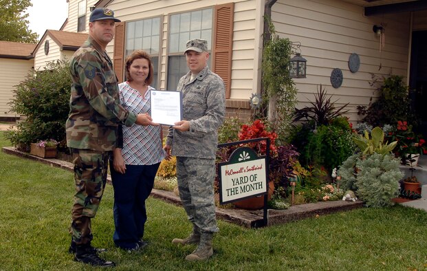 Lt. Col. Roman Hund, 22nd Mission Support Group deputy commander, recognizes Master Sgt.  Scott Schindler, 22nd Maintenance Operations Squadron, and spouse Lanee Schindler Sept. 2 at their home for winning Southwind Housing Yard of the Month at McConnell Air Force Base, Kan., for August. Yard of the month winners earn the award for having the best-looking or kept yard in housing for that month. The competition is annual and runs from May to September. (U.S. Air Force photo/Senior Airman Anthony Mejia)