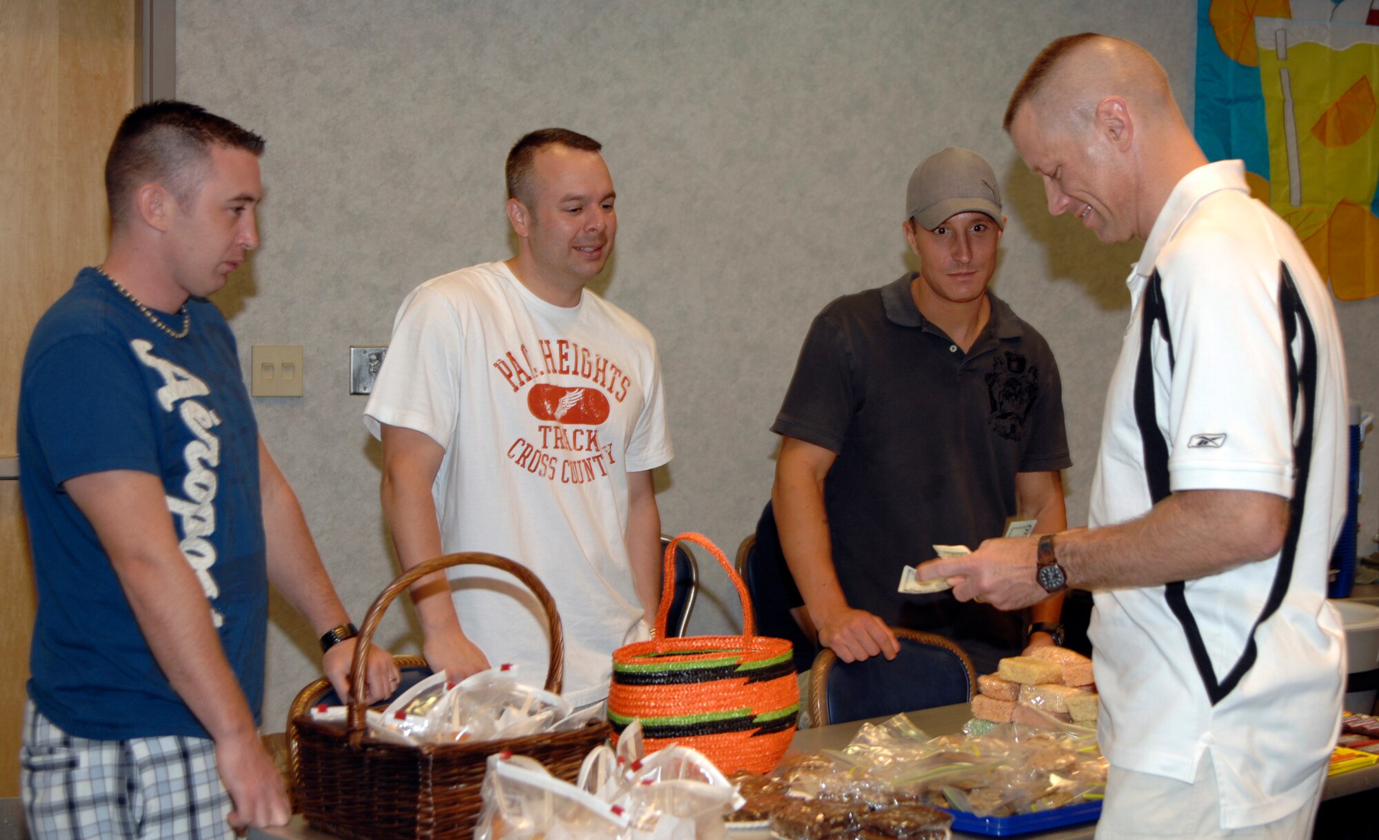 The 22nd Communications Squadron’s Staff Sgt. Charles Galloway, Tech. Sgt. Brad Schafer and Senior Airman John Mass, sell candied goods to their commander, Lt. Col. Sean Robinson, at a MatchUp finale party at McConnell Air Force Base, Kan., Sept. 3. MatchUp is an Air Material Command online game that awards bases prizes based on participation and luck. McConnell finished No. 1 in the command when the competition ended Aug. 31. Six Team McConnell members won prizes at the event, to include five, $100 cash prizes and a $500 grand prize. (U.S. Air Force photo/Senior Airman Laura Suttles)