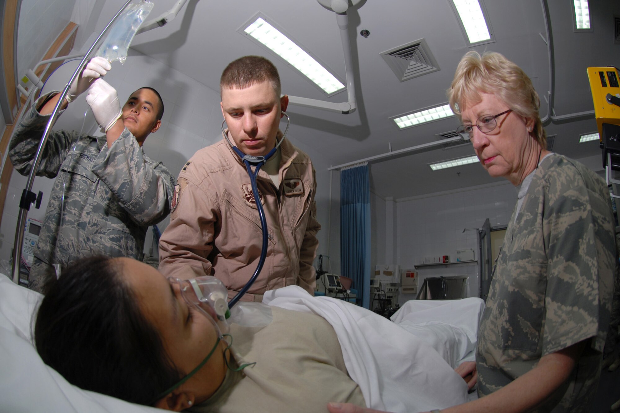 Left, Senior Airman Anthony Suemai, 379th Expeditionary Medical Group aerospace medical technician prepares an IV bag while Capt. (Dr.) Andrew Clark, flight surgeon, and Lt. Col. Glory Meade, preoperative nurse, assess a patient, here Sept. 10. The 379 EMDG, in addition to healthcare provided to the 9,000 servicemembers here, also provides medical care to wounded warriors. Airman Suemai is deployed from Peterson Air Force Base, Colo. Doctor Clark is deployed from Lackland Air Force Base, Texas. Colonel Meade is deployed from Wright Patterson Air Force Base, Ohio. All are deployed in support of Operations Iraqi and Enduring Freedom. (U.S. Air Force Photo/Tech. Sgt. Jason W. Edwards)