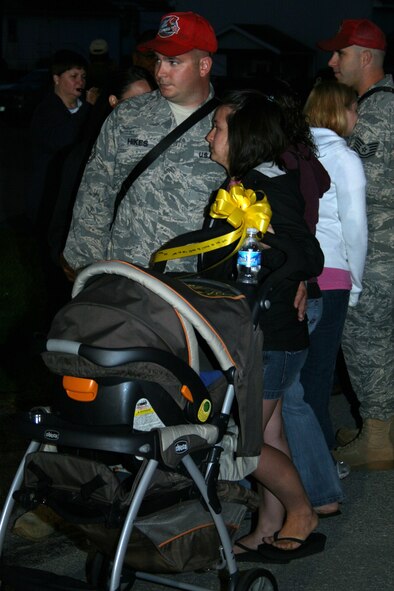 Tech. Sgt. Andrew Hikes, of the 201st RED HORSE squadron, embraces his wife, Tammy, as they wait in line with their three-month-old son to hang their yellow ribbon on the fence of the RED HORSE compound.  