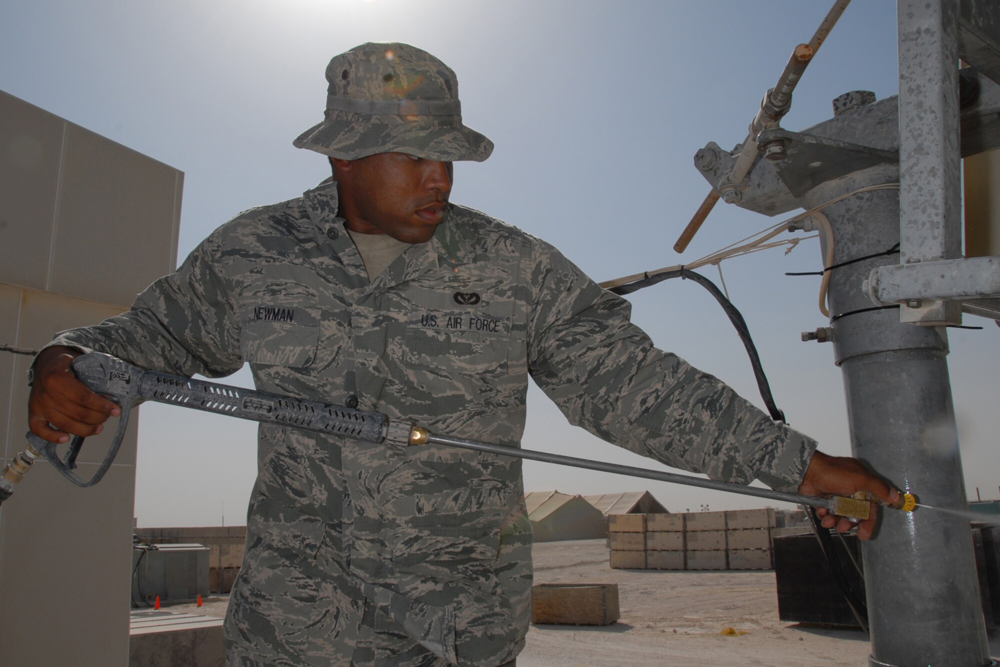 Airman 1st Class Aaron Newman, 379th Expeditionary Civil Engineer Squadron heating, ventilation and air conditioning journeyman, pressure washes an audio/video satellite uplink dish, here, Sept. 10. The dish is used for live audio and video broadcasts to support live feeds to worldwide media outlets. Airman Newman is deployed from Eielson Air Force Base, Alaska in support of Operations Iraqi and Enduring Freedom.  (U.S. Air Force Photo/Tech. Sgt. Jason W. Edwards)