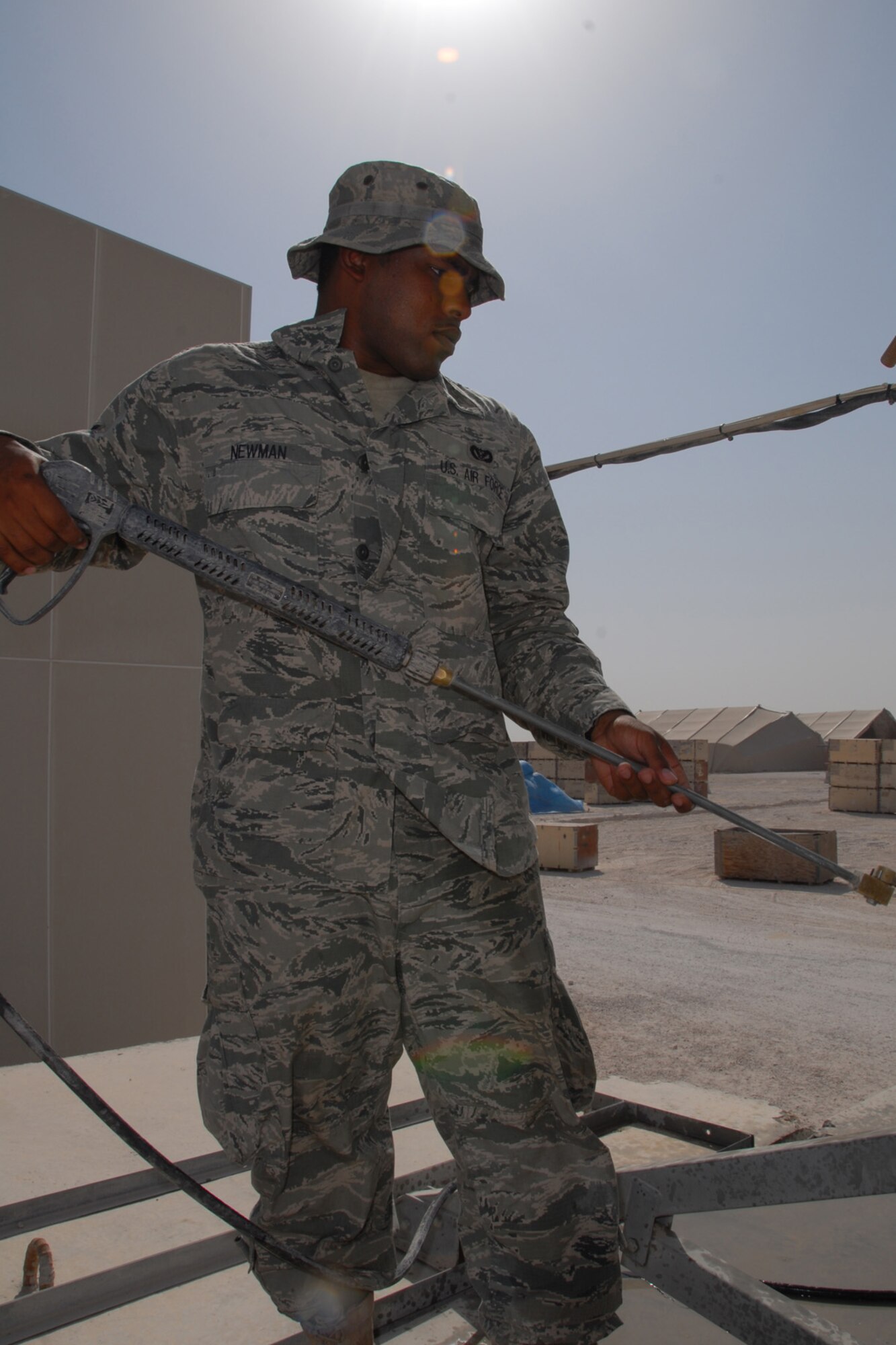 Airman 1st Class Aaron Newman, 379th Expeditionary Civil Engineer Squadron heating, ventilation and air conditioning journeyman, pressure washes an audio-video satellite uplink dish, here, Sept. 10. The dish is used for live audio and video broadcasts to support live feeds to worldwide media outlets. Airman Newman is deployed from Eielson Air Force Base, Alaska in support of Operations Iraqi and Enduring Freedom.  (U.S. Air Force Photo/Tech. Sgt. Jason W. Edwards)