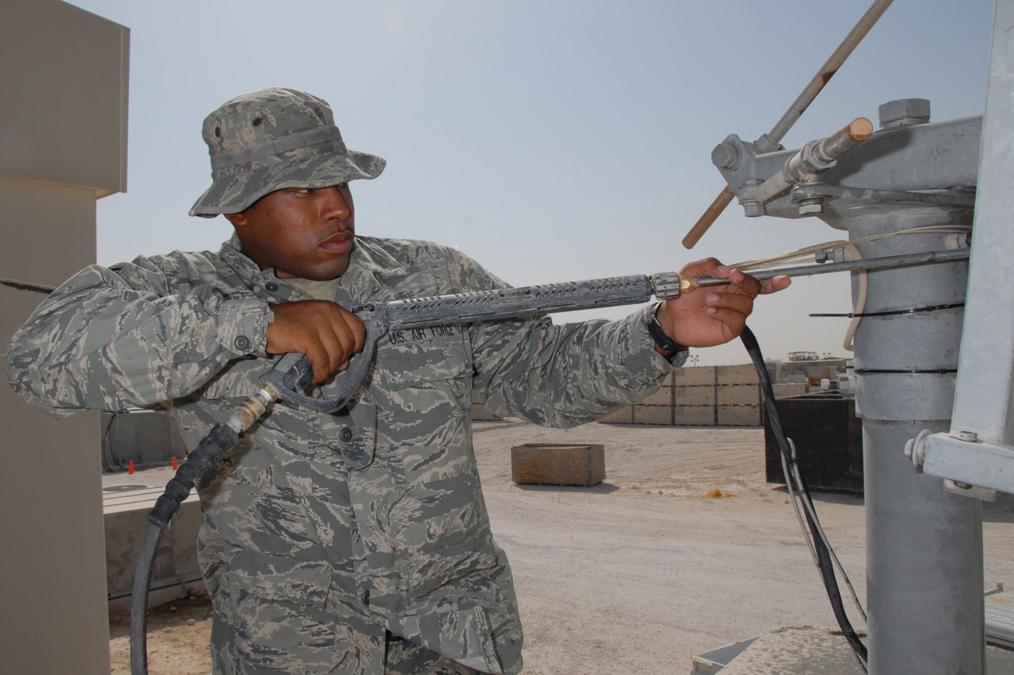 Airman 1st Class Aaron Newman, 379th Expeditionary Civil Engineer Squadron heating, ventilation and air conditioning journeyman, pressure washes an audio/video satellite uplink dish, here, Sept. 10. The dish is used for live audio and video broadcasts to support live feeds to worldwide media outlets. Airman Newman is deployed from Eielson Air Force Base, Alaska in support of Operations Iraqi and Enduring Freedom.  (U.S. Air Force Photo/Tech. Sgt. Jason W. Edwards)