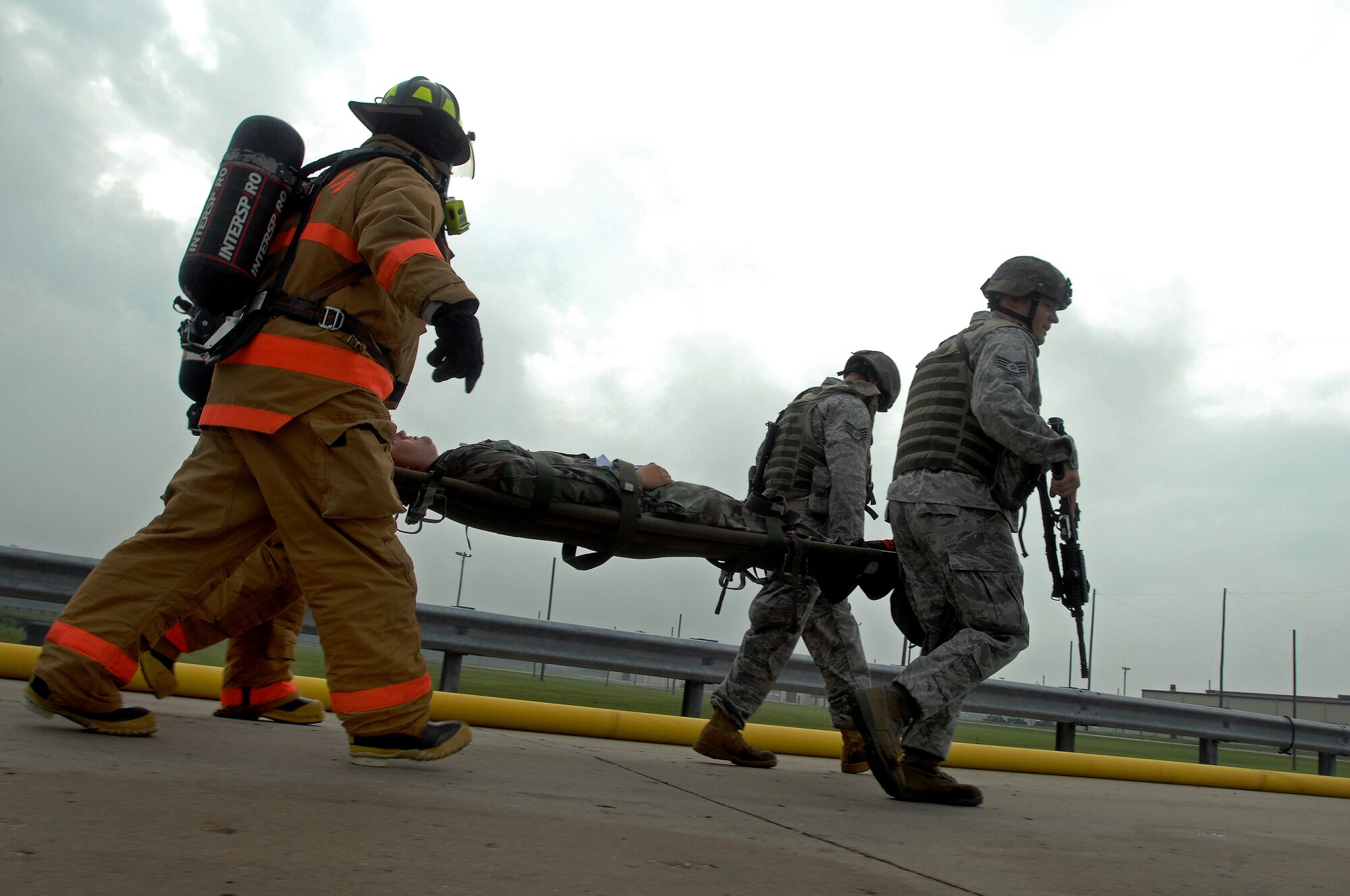 WHITEMAN AIR FORCE BASE, Mo. - 509th Civil Engineer Squadron firefighters and Security Forces Squadron members carry Airman 1st Class Richard May, 509th Munitions Squadron weapons technician, to a medical tent after suffering simulated wounds from a weapons fire during a Mass Accident Response Exercise, Sept. 9. Airmen participating in the exercise were faced with a weapons transport that had come under enemy fire, resulting in injured casualties, a contamination spill and an ignited B-61 missile.  Firefighters, security forces, medical, explosive ordinance and munitions personnel all played major roles in the exercise to successfully complete all tasks and meet training requirements. (U.S. Air Force photo/Senior Airman Kenny Holston) 