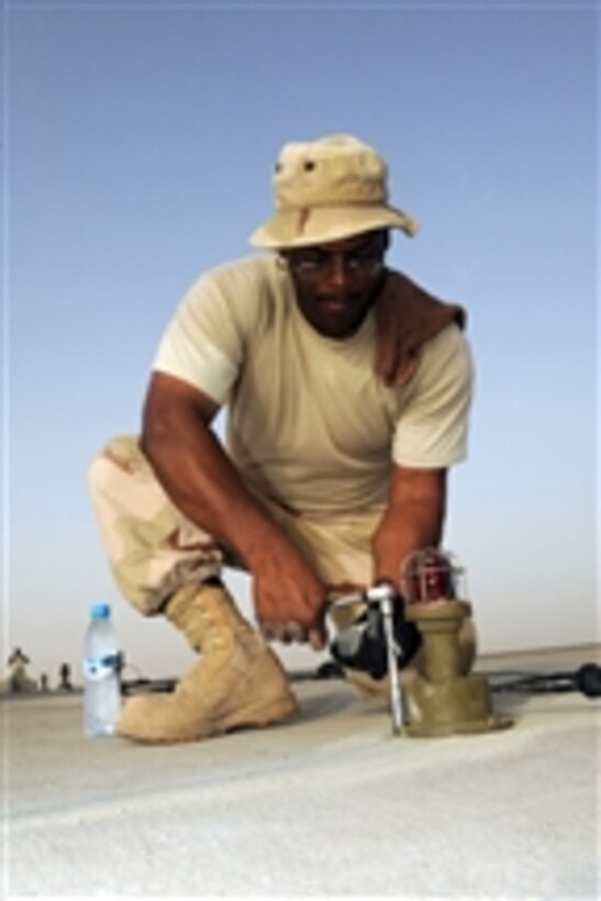U.S. Air Force Master Sgt. Darryl Harris, with the 380th Civil Engineer Squadron, tightens the bolts on a runway light at a location in Southwest Asia on Aug. 15, 2009.  Harris is deployed from Spangdahlem Air Base, Germany.  