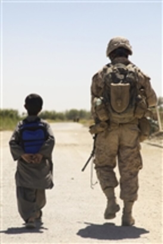 U.S. Marine Corps Cpl. Christopher Mullins, with Headquarters and Service Company, 1st Battalion, 5th Marine Regiment, patrols through the Nawa bazaar with an Afghan boy in the Nawa district of Helmand province, Afghanistan, on Sept. 8, 2009.  The Marines are deployed with Regimental Combat Team 3 to conduct counterinsurgency operations with Afghan National Security Forces in southern Afghanistan.  