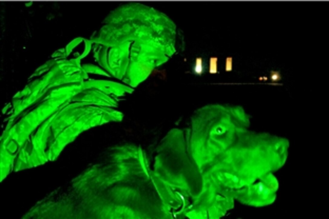 A U.S. Army soldier sits with his dog awaiting transport to another location on Contingency Operating Base Speicher in northern Iraq, Sept. 8, 2009. U.S. aviation soldiers with the 10th Mountain Division's 3rd Brigade Combat Team fly CH-47 Chinooks helicopters and deliver cargo to other forward operating locations in northern Iraq.