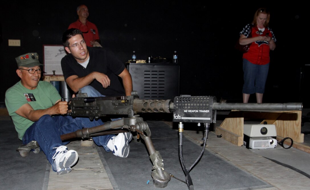 Marine Veteran Steve Lara, fires a simulated machine gun, in the School of Infantry's Indoor Simulated Marksmanship Trainer while taking some advice from Eric Harding, ISMT technician, SOI, Camp Pendleton, during a Vietnam veterans' tour, Sept. 10.