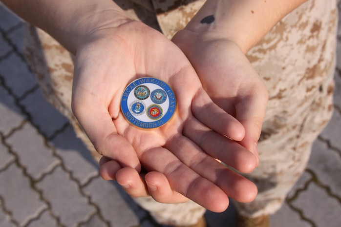 A Marine holds one of the 9/11 Remembrance coins given out by Marine Corps Community Services at the Freedom Walk held here Sept. 11. The youngest Marines in attendance at the Freedom Walk were in elementary school during the attacks on Sept. 11, 2001.