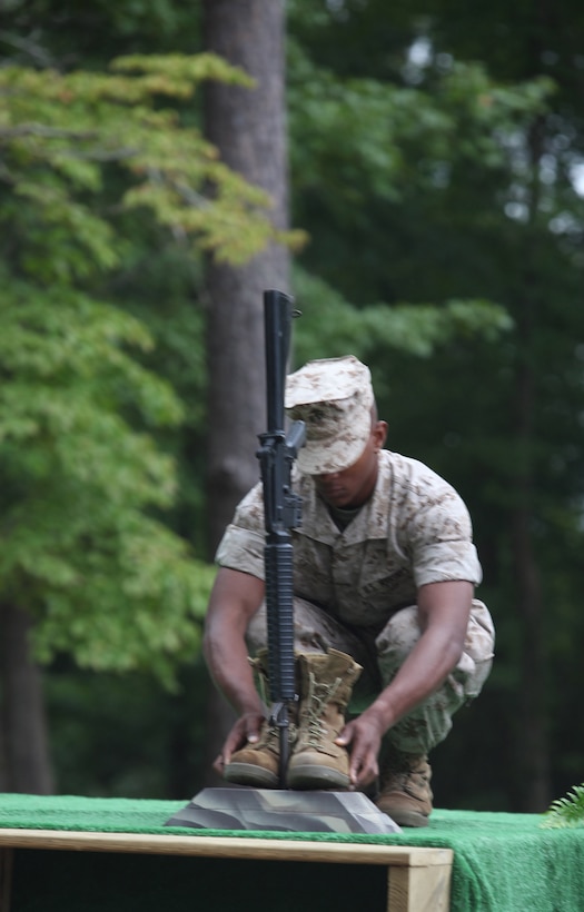 A Marine places combat boots beside a rifle as part of a memorial to symbolize  those who lost their lives in Operations Iraqi and Enduring Freedom during a 9/11 remembrance ceremony at Lejeune Memorial Gardens Sept. 11. The ceremony, sponsored by the Onslow Civil Affairs Committee, read stories of those who died in the terrorist attacks to help give a human face to the victims.