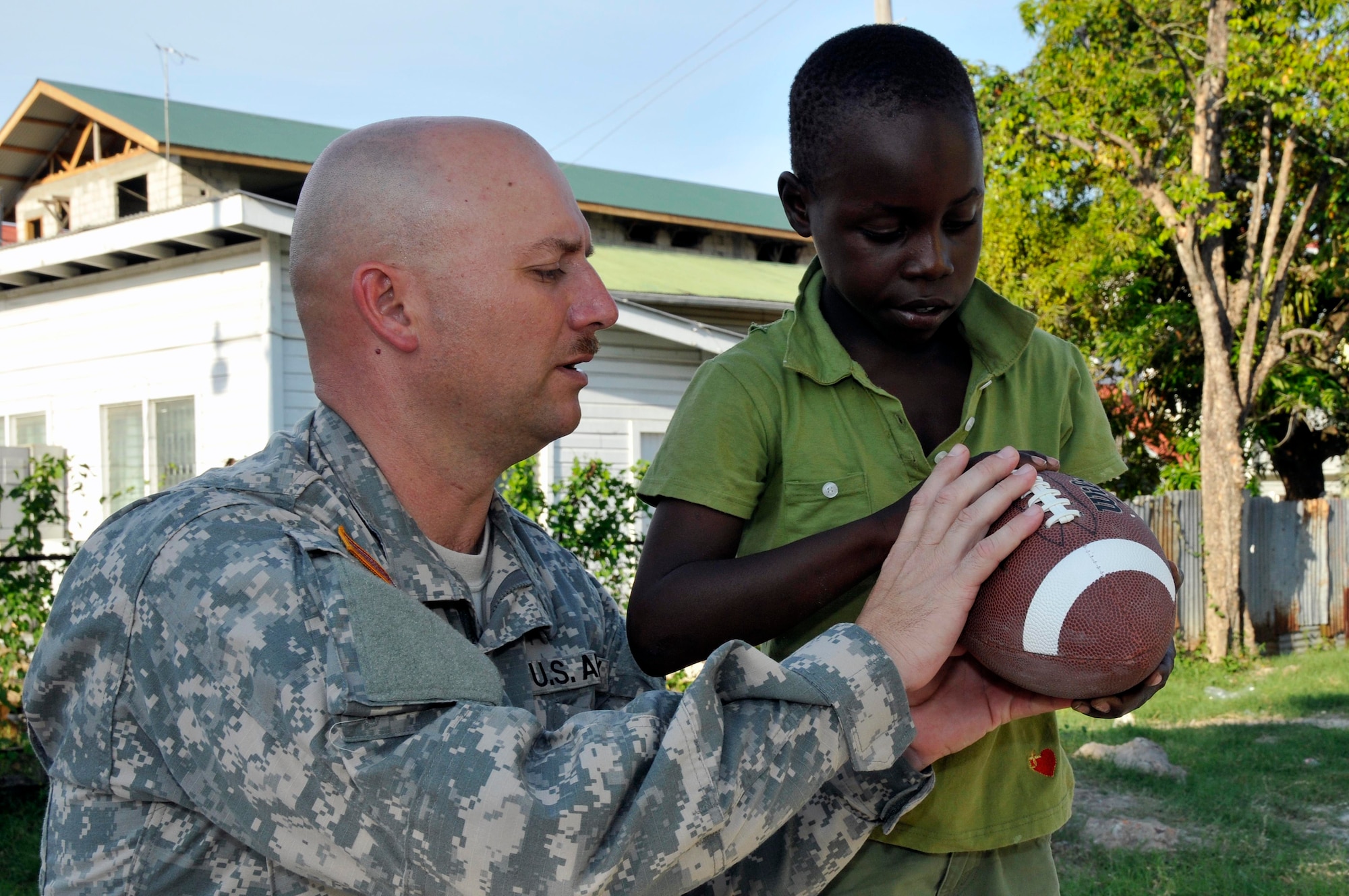 Command Sgt. Maj. Lynward Hall, with the 878th Engineer Battalion, Georgia Army National Guard, shows a Guyanese boy how to throw a football at the Joshua's Place Orphanage Sept. 9, 2009. Hall's battalion brought 32 duffel bags of toys and clothes and over $3,800 in donated items to the orphanage. (U.S. Air Force photo by Airman 1st Class Perry Aston) (Released)