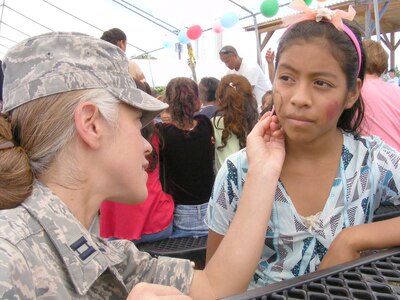 SOTO CANO AIR BASE, Honduras — Capt. Margaret Baucom, Joint Task Force-Bravo protocol officer, paints Dunia Mazariegos face during the JTF-Bravo’s “kid’s day” Sept. 10 near the base soccer field. More than 100 children from local orphanages were transported to base for the day The children participated in a variety of events the volunteers organized including a HH-60 Blackhawk static display, military working dog demonstration and fire truck display. The children also got to participate in soccer, kickball and a water balloon toss. A free lunch was also served and the children were given a “goodie” bag containing small toys and candy as the left base (U.S. Air Force photo/Martin Chahin).