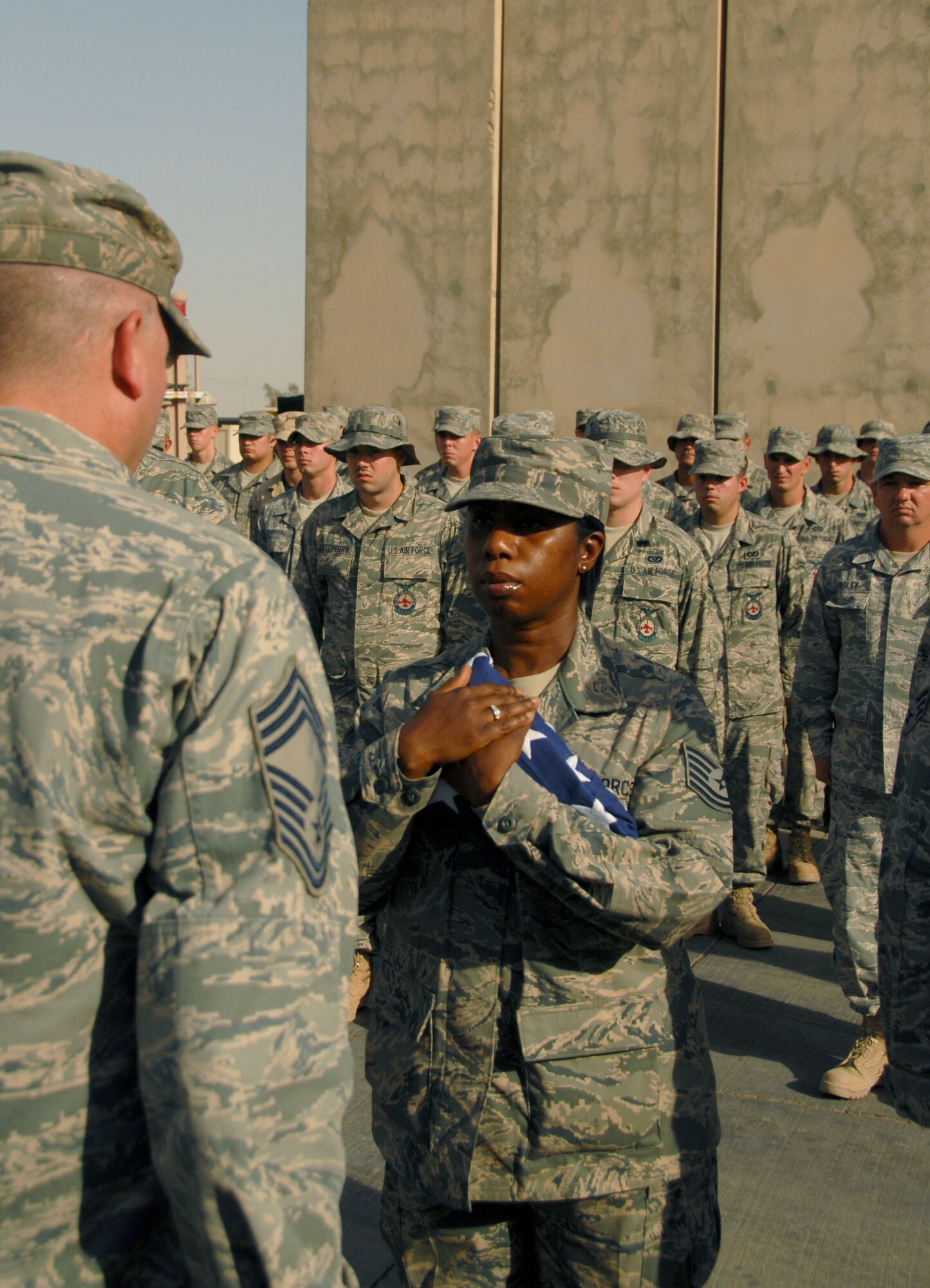 JOINT BASE BALAD, Iraq -- Tech. Sgt. Nadine Pinto, 332nd Expeditionary Logistics Readiness Squadron aerial port data records manager, receives an American flag from Chief Master Sgt. Lawrence Rettele, 332nd Expeditionary Security Forces Group superintendent, during a Last Alarm ceremony at the JBB fire station here Sept. 11, 2009. Sergeant Pinto is a Reservist deployed here from the 88th Aerial Port Squadron at McGuire Air Force Base, N.J., and she also serves in the New York Police Department. In response to the terrorist attacks on Sept. 11, 2001, she performed evidence control for the department. (U.S. Air Force photo/Senior Airman Nicole Enos)