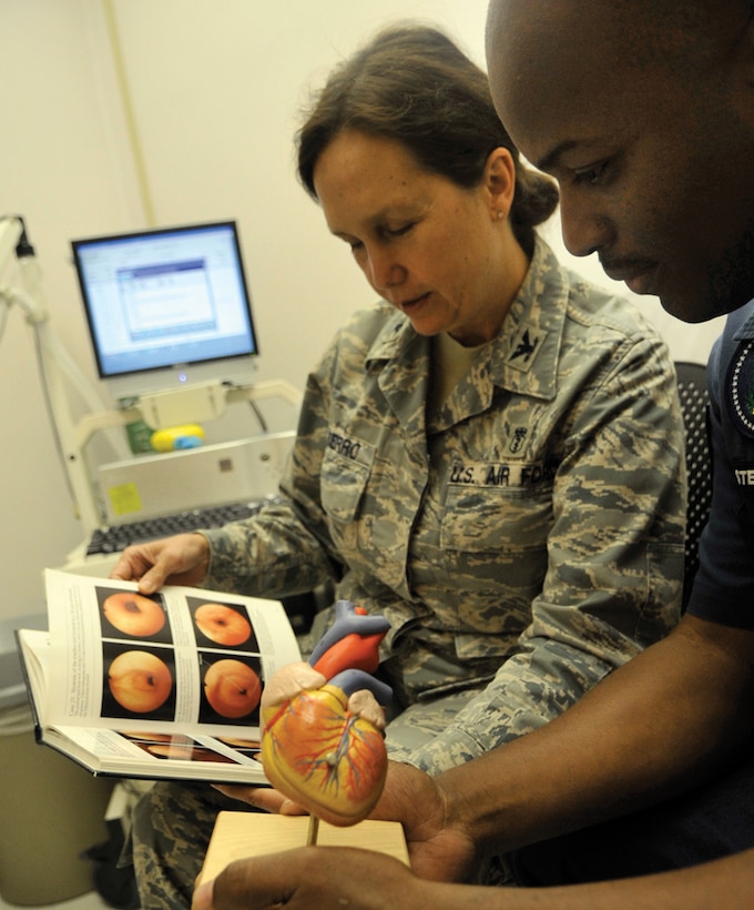 Colonel Eva Berro, 779th Medical Operations Squadron chief pulmonologist, reads information about the heart and lungs to Tech. Sgt. Craig Stewart, 89th Presidential Logistics Squadron crew chief, during his appointment at Malcolm Grow Medical Center Tuesday. As a doctor in the clinic, it is her duty to not only treat her patients, but to keep them well informed. (U.S. Air Force photo/ Staff Sgt. Renae Kleckner)