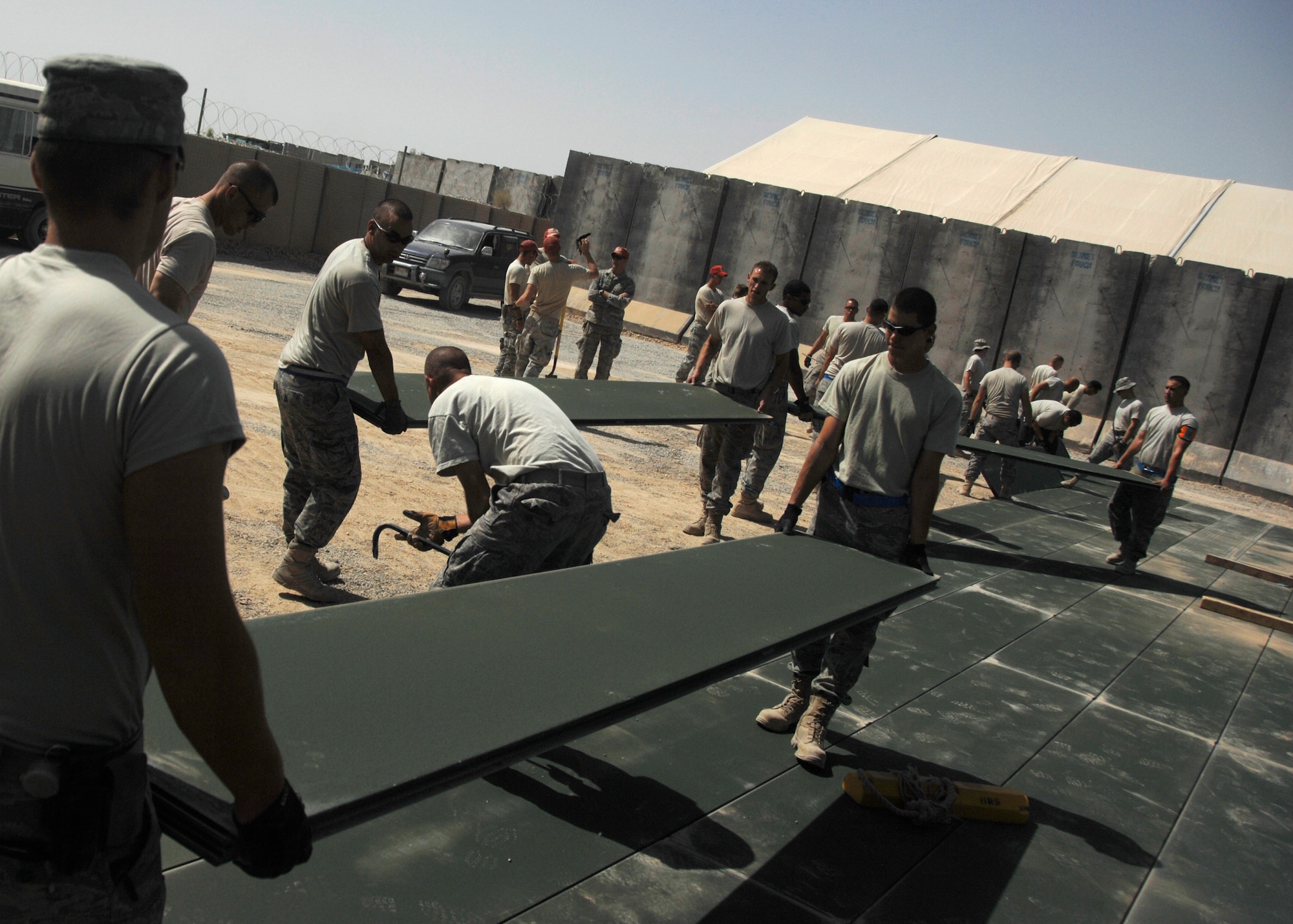 Several pairs of civil engineers carry 150-pound AM2 mats into place at Panther Ramp here, Sept. 10, 2009. Depending on the use and location, dozens of mats may need to be hand laid in place to form things such as temporary runways in deployed locations. (U.S. Air Force photo/Senior Airman Timothy Taylor)