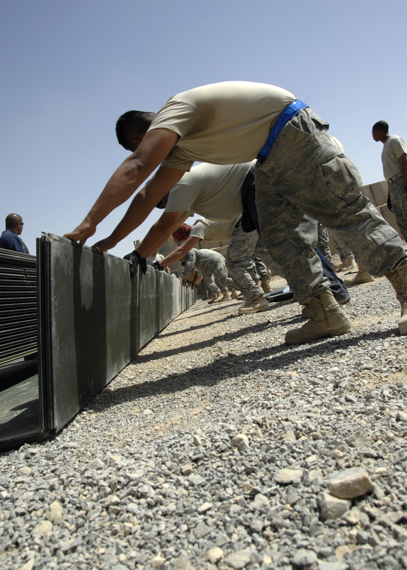 KANDAHAR AIR FIELD, Afghanistan – Members from the 451st Civil Engineering Squadron work together to fix a problem with a crease between the AM-2  matting here, Sept. 10, 2009. Two-men teams were used to carry the dozens of mats that were laid that day, each weighing approximately 150 pounds apiece. AM-2  matting is also used in the construction of temporary runways in deployed locations. (U.S. Air Force photo/Senior Airman Timothy Taylor)