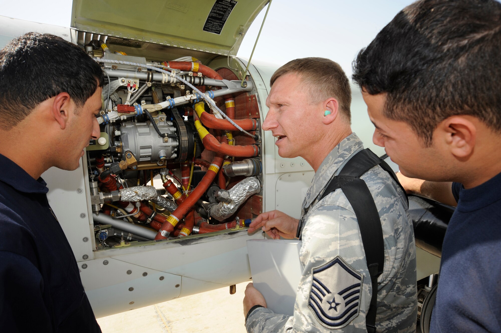NEW AL MUTHANNA AIR BASE, Iraq -- Master Sgt. John Theiral, 321st Air Expeditionary Advisor Squadron King Air maintenance senior advisor, shows Iraqi airmen how to conduct post flight inspections in an aft engine compartment here Sept. 5, 2009. The inspections involve looking for fuel and hydraulic leaks and checking the aircraft's air conditioning serpentine belt for wear. Sergeant Theiral is deployed from Scott Air Force Base, Ill., and is a native of Roseburg, Ore.  (U.S. Air Force photo/Tech. Sgt. Johnny L. Saldivar)