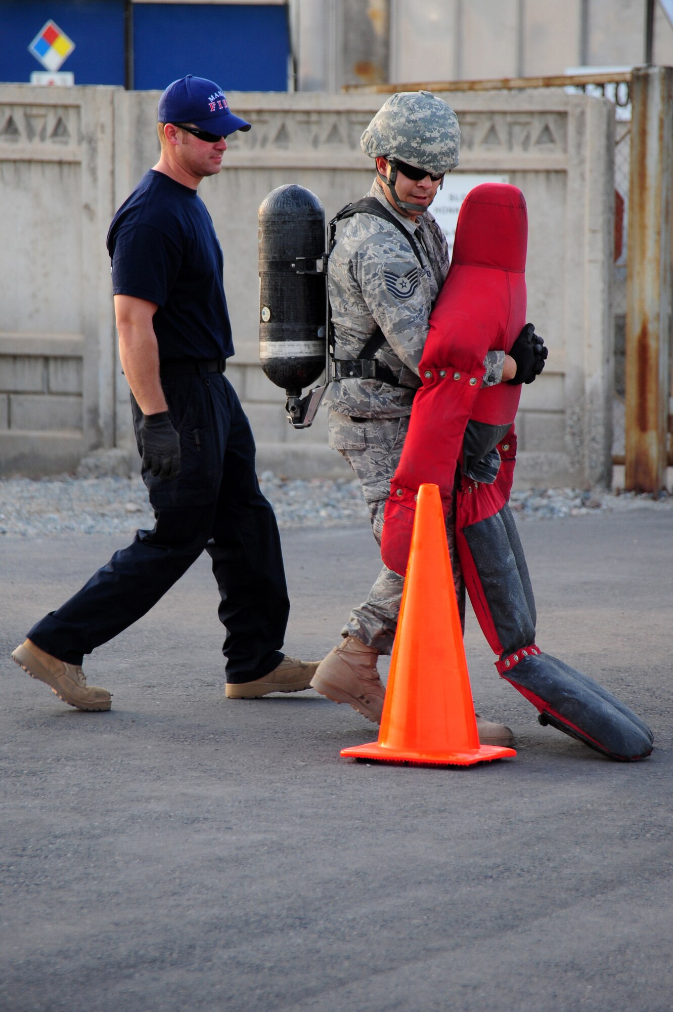 TRANSIT CENTER AT MANAS, Kyrgyzstan -- Tech. Sgt. Gabriel Antone, 376th Air Expeditionary Wing chaplain assistant, performs the simulated victim removal exercise while Mr. Matthew Cook, 376th Expeditionary Civil Engineer Squadron fire captain, ensures safety during the Fire Fighter Challenge at the Transit Center. Dragging the one-hundred ninety pound 'victim' was no easy feat during the challenge provided by the Manas fire team. (U.S. Air Force photo/Senior Airman Steele C. G. Britton)