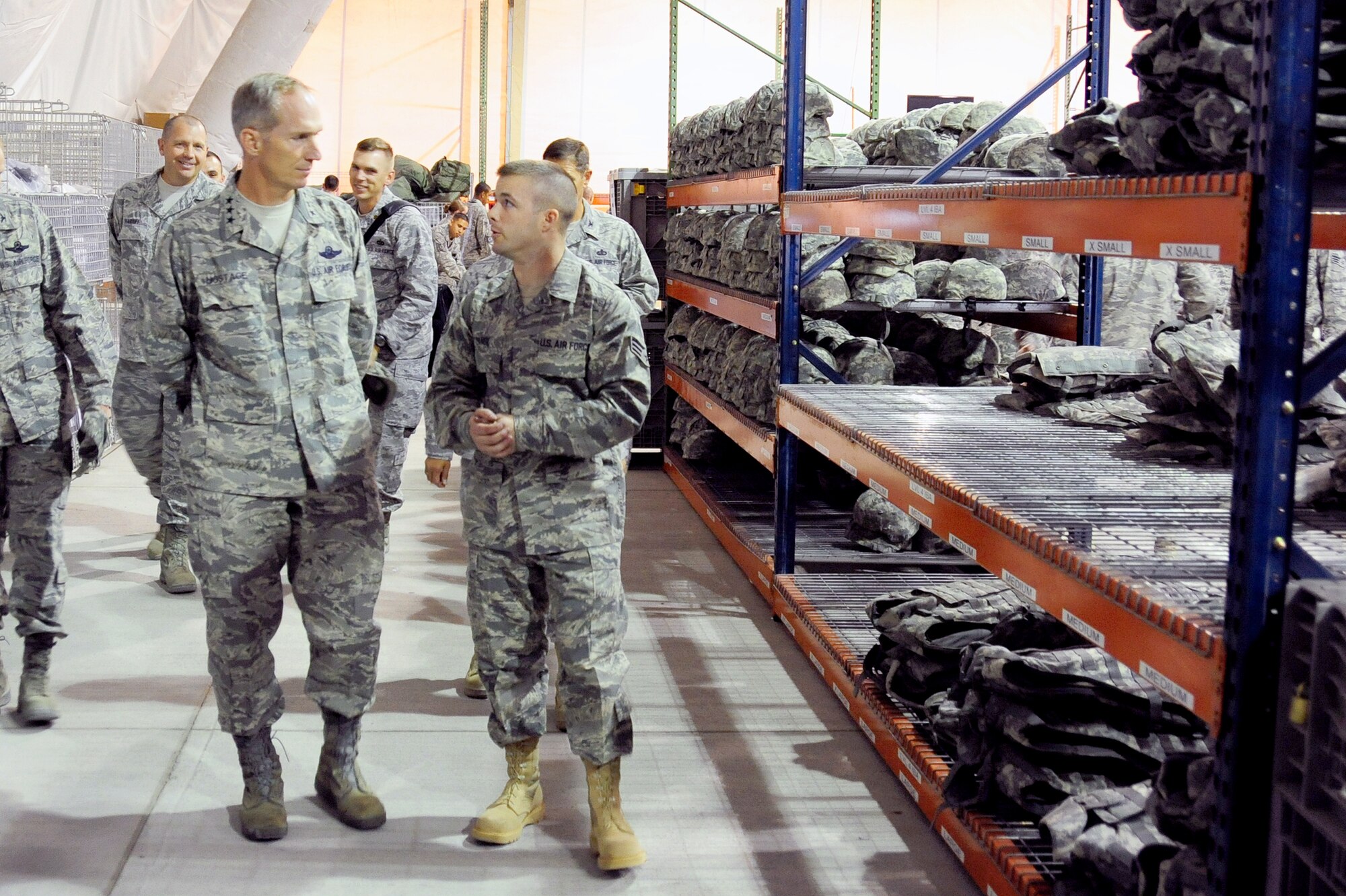 TRANSIT CENTER AT MANAS, Kyrgyzstan -- Lt. Gen. Mike Hostage, U.S. Air Force Central Command commander, is toured by Senior Airman Kyle Zangl, 376th Expeditionary Logistics Readiness Squadron theater distribution center technician, through the Expeditionary Theater Distribution Center at the Transit Center. The Manas ETDC is one of only three of its kind in the AOR. General Hostage toured the Transit Center at Manas for the first time as AFCENT commander. He visited several facilities at Manas and shared his time with Airmen stationed here. (U.S. Air Force photo/Senior Airman Steele C. G. Britton)