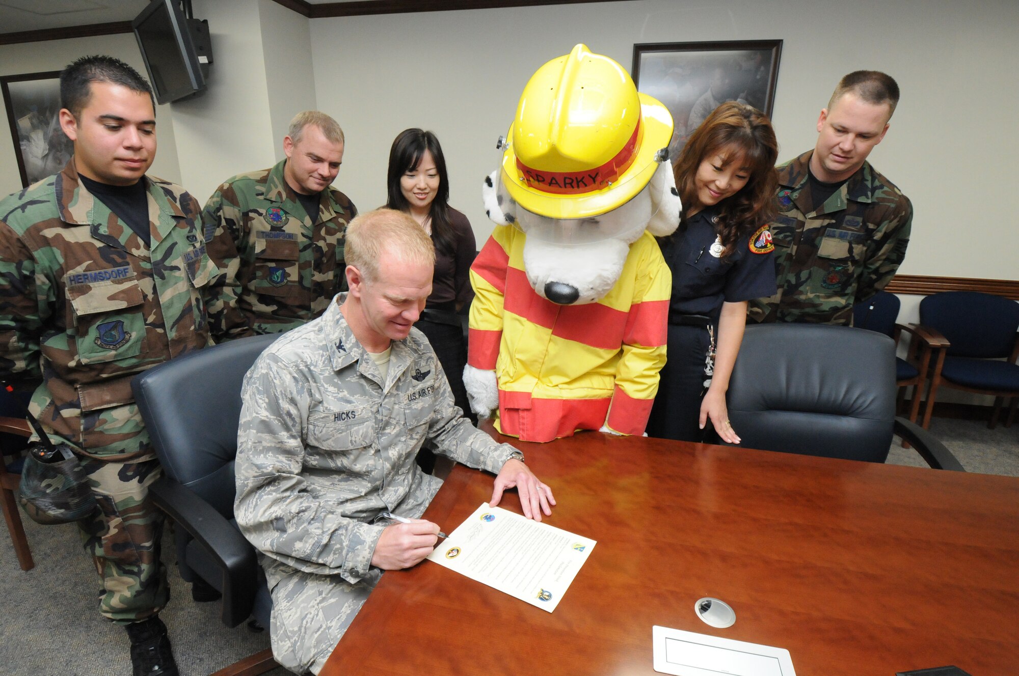 YOKOTA AIR BASE, Japan -- Col. J. Marcus Hicks, 374th Airlift Wing commander, signs a proclamation letter declaring Oct. 13-17 as fire prevention week here as Sparky the Fire Dog and other members of the Yokota Fire Department look on. During fire prevention week the fire department will sponsor activities for children across the base to educate children and their parents on fire prevention and detection. (U.S. Air Force photo/Staff Sgt. Veronica Pierce)